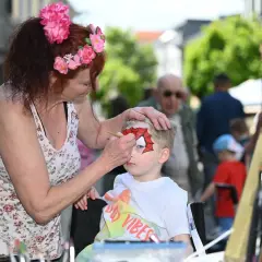 Kind wird beim Stadtfest in Radevormwald von einer Frau mit Spiderman-Maske bemalt.