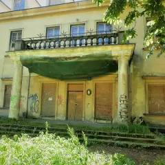 Zaniedbany pałac Tarnowskich w Krakowie, z zabitymi deskami oknami i drzwiami, pokryty graffiti.