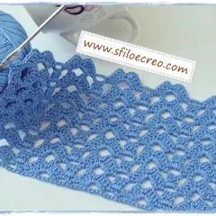 Uncinetto con filato azzurro crea un motivo a **punti traforati uncinetto** con un bordo ondulato.