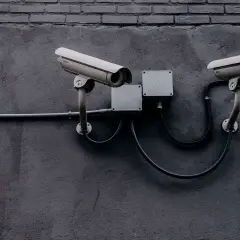 Deux caméras de surveillance fixées sur un mur sombre, évoquant la législation sur la vidéosurveillance et la protection des données.