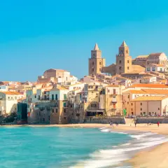 La costa di Cefalù con le sue case colorate e il mare azzurro. La cattedrale domina il panorama.