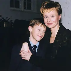 Uśmiechnięty Mateusz Matczak, syn Pieńkowskiej, w garniturze, przytulony do mamy.