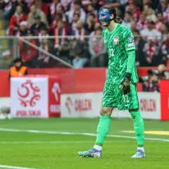 Kamil Grabara w zielonym stroju bramkarskim i niebieskiej masce na twarzy, gotowy do gry w barwach swojej obecnej drużyny.