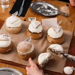 En härlig samling semlor med fluffig grädde och flaggor. En semla är uppskuren, redo för en smak av ritorno semla.