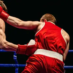 Boxers in a ring. The boxer in red throws a punch, showing how to know if your southpaw or orthodox by their stance.