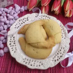Pyszne rogaliki z kajmakiem na talerzyku, ozdobione wstążkami i tulipanami.