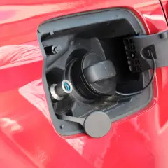 Tapa de combustible de un coche que usa GLP, con boquilla azul y tapón negro.