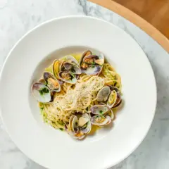 Spaghetti aux coques, une recette italienne savoureuse, garnie de parmesan râpé et d'herbes fraîches.