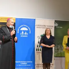 Biskup sosnowiecki przemawia na tle banerów kampanii przeciw przemocy w rodzinie i MOPS Sosnowiec.