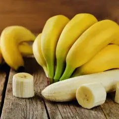 Kilka dojrzałych bananów, jeden obrany i pokrojony, na drewnianym blacie. Zastanawiasz się, ile cukru ma banan?