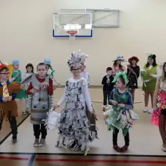 Dzieci prezentują stroje na Dzień Wiosny. Chłopiec w brązowym stroju z frędzlami, obok niego chłopiec w stroju z butelek.