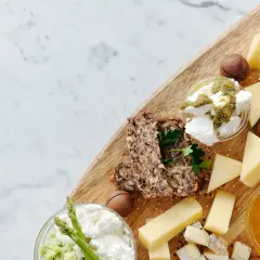 Tagliere con formaggi poco stagionati, pane integrale, frutta secca e miele.