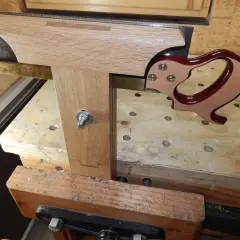 Un guide en bois et laiton aide à comment affûter une lame de banc de scie. La lame est tenue dans un étau.