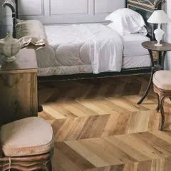 Sypialnia z łóżkiem i meblami, podłoga w jodełkę z kolekcji Marazzi Treverksoul Neutral.