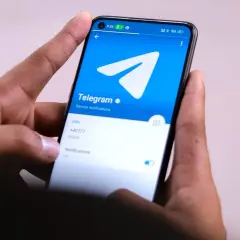 Dłonie trzymają smartfon z otwartą aplikacją Telegram. Widać logo i opcje powiadomień, idealne do dyskretnych rozmów w tajnych grupach Telegram.