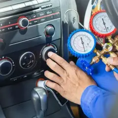 Mechanik sprawdza ciśnienie czynnika klimatyzacji R1234yf za pomocą manometrów.