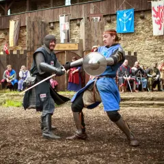 Zwei Ritter im Kampf bei den ritterspielen auf einer Burg. Zuschauer beobachten das Spektakel.