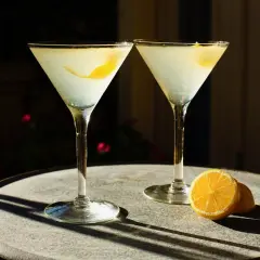Dwa drinki z wódką waniliową i cytryną, podane w kieliszkach martini na kamiennym stoliku.