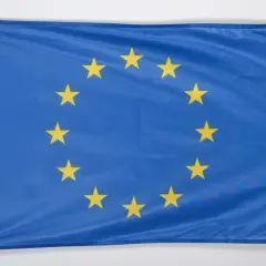 Flaga Unii Europejskiej z dwunastoma złotymi gwiazdami na niebieskim tle.