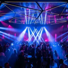 Une foule danse sous des jeux de lumière bleus et roses dans une salle de concert, évoquant l'ambiance d'un "phantom Paris" nocturne.