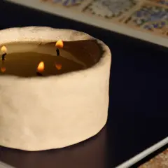 Świeca w ceramicznym naczyniu z trzema płonącymi knotami.