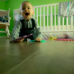 Wesołe dziecko kiedy dziecko raczkuje, bawi się kolorowymi puzzlami na podłodze w pokoju dziecięcym.