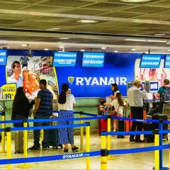 Odprawa online Ryanair ułatwia podróżowanie. Ludzie z bagażami czekają w kolejce do stanowisk odprawy.