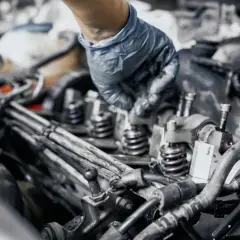 Mano enguantada trabajando en los inyectores de un coche, parte esencial para la combustión.