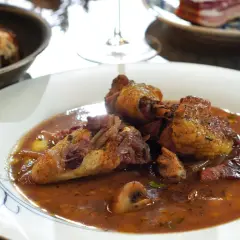 Ein köstliches Coq au Vin Rezept: zartes Hähnchen in Rotwein-Sauce mit Speck und Pilzen, serviert mit Brot.