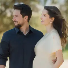 Para księcia Husseina i Rajwy Al Saif, oczekujących na dziecko, patrzą w dal na tle natury.