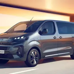 Nowy Peugeot e-Traveller, czyli ile waży bus 9-osobowy, pędzi po drodze na tle pomarańczowych ścian.