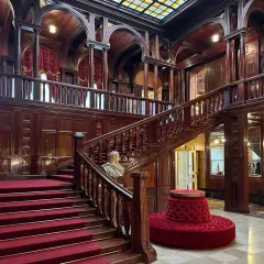 Elegancka klatka schodowa z czerwonym dywanem i rzeźbą. Wspaniałe wnętrze, które warto zobaczyć, zwiedzając okolice Łodzi atrakcje.