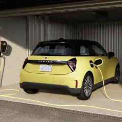 Żółty elektryczny Cooper w garażu, podłączony do ładowarki. Idealny wybór dla leasingu konsumenckiego samochodu.