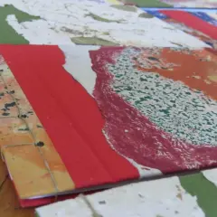 Dettaglio di come rilegare fogli a mano con filo, creando un quaderno artistico con copertina colorata.