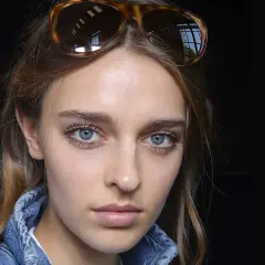 Ragazza con occhiali da sole in testa, viso illuminato da fondotinta e fard, ciglia lunghe e occhi azzurri.