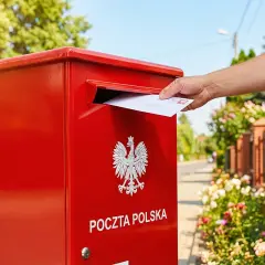 Mężczyzna wrzuca list do czerwonej skrzynki Poczty Polskiej. Kto to? Nadawca, który wysyła wiadomość.