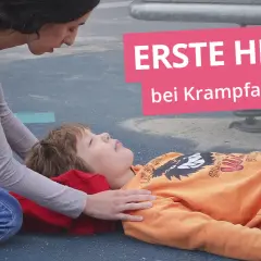 Erste Hilfe bei Krampfanfällen: Eine Frau kniet neben einem Kind, das auf dem Boden liegt.