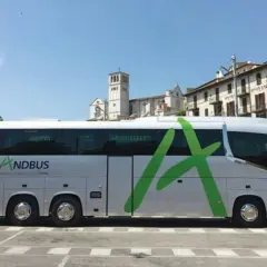 Autokar ANDBUS, idealny na podróż z Barcelony do Andory, parkuje przed zabytkową zabudową.