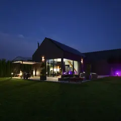Nowoczesny dom pasywny nocą, z oświetlonym ogrodem i tarasem. Cena takiego domu jest inwestycją w przyszłość.