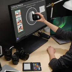 Kobieta wykonuje kalibrację drukarki, używając kalibratora na ekranie monitora.