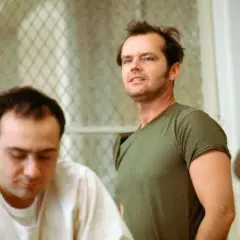 Jack Nicholson, con sguardo intenso, incarna la ribellione nel film "Qualcuno volò sul nido del cuculo", sfidando l'autorità in un contesto di reclusione.