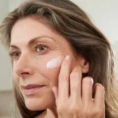 Frau trägt abends keine Creme ins Gesicht, sondern nur einen Tupfer auf die Wange.
