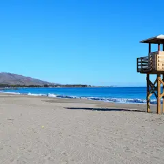 Torre de vigilancia de madera en la playa de Vera, con arena y mar azul. La playa de Vera tiene piedras, pero hoy el sol brilla.