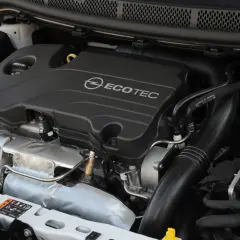 Silnik Opel Astra 1.4 Turbo Ecotec. Widoczny turbosprężarka, kolektor dolotowy i osłona silnika.