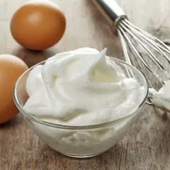 Ubite białka jaj w miseczce, obok dwa jajka i trzepaczka. Idealne do bezy, musów i innych deserów.