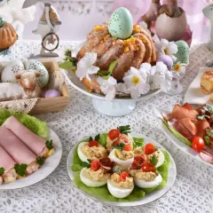 Wielkanocny stół pełen smakołyków: babka, jajka faszerowane, wędliny, ciasto. Idealne inspiracje, co ugotować na święta.