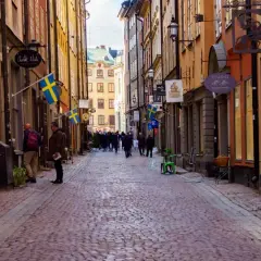 En mysig vandring i Gamla Stan med kullerstensgator, svenska flaggor och historiska byggnader.