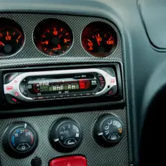 Deska rozdzielcza samochodu z radiem i wskaźnikami. W tle widać panel z włókna węglowego, który może przypominać o opłatach, jak podatek od radia w samochodzie.