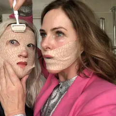 Två kvinnor med ansiktsmasker. En använder en microneedling-roller. Frågan om microneedling hemma hur ofta är relevant för denna typ av behandling.