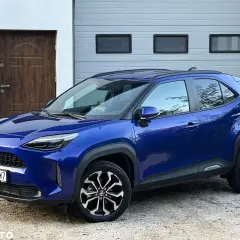 Niebieski Toyota Yaris Cross Hybrid 2022 na tle garażu. Sprawdź jego atrakcyjną cenę!